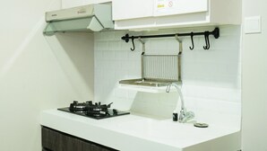 A kitchen with a gas stove, a sink, and a hanging rack.