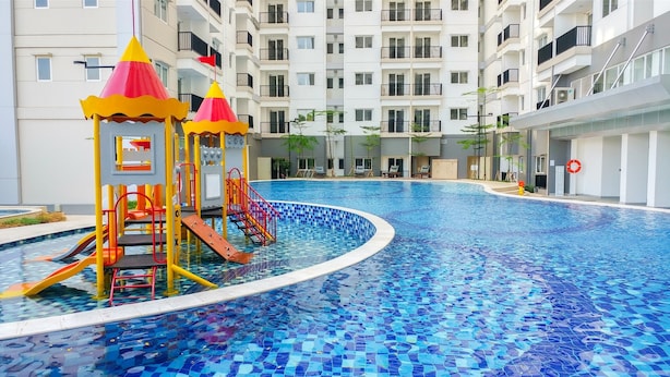 A swimming pool with a children's play area, surrounded by a multi-story residential building.