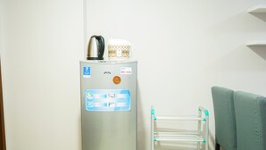 A compact kitchenette with a water dispenser, a kettle, and a small refrigerator.