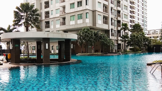 Ein Swimmingpool mit einer kreisförmigen Struktur in der Mitte, umgeben von einem mehrstöckigen Gebäude mit Balkonen.