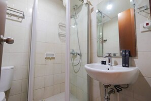 Ein Badezimmer mit einer Duschkabine, einem weißen Waschbecken und einem Spiegel.