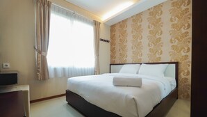Ein ordentlich bezogenes Bett mit weißen Leinen, ein Nachttisch und ein Fenster mit Vorhängen.