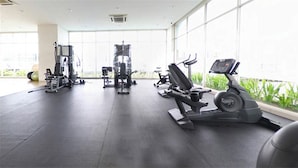 Ein Fitnessstudio mit diversen Trainingsgeräten, großen Fenstern und Blick auf Grünflächen.
