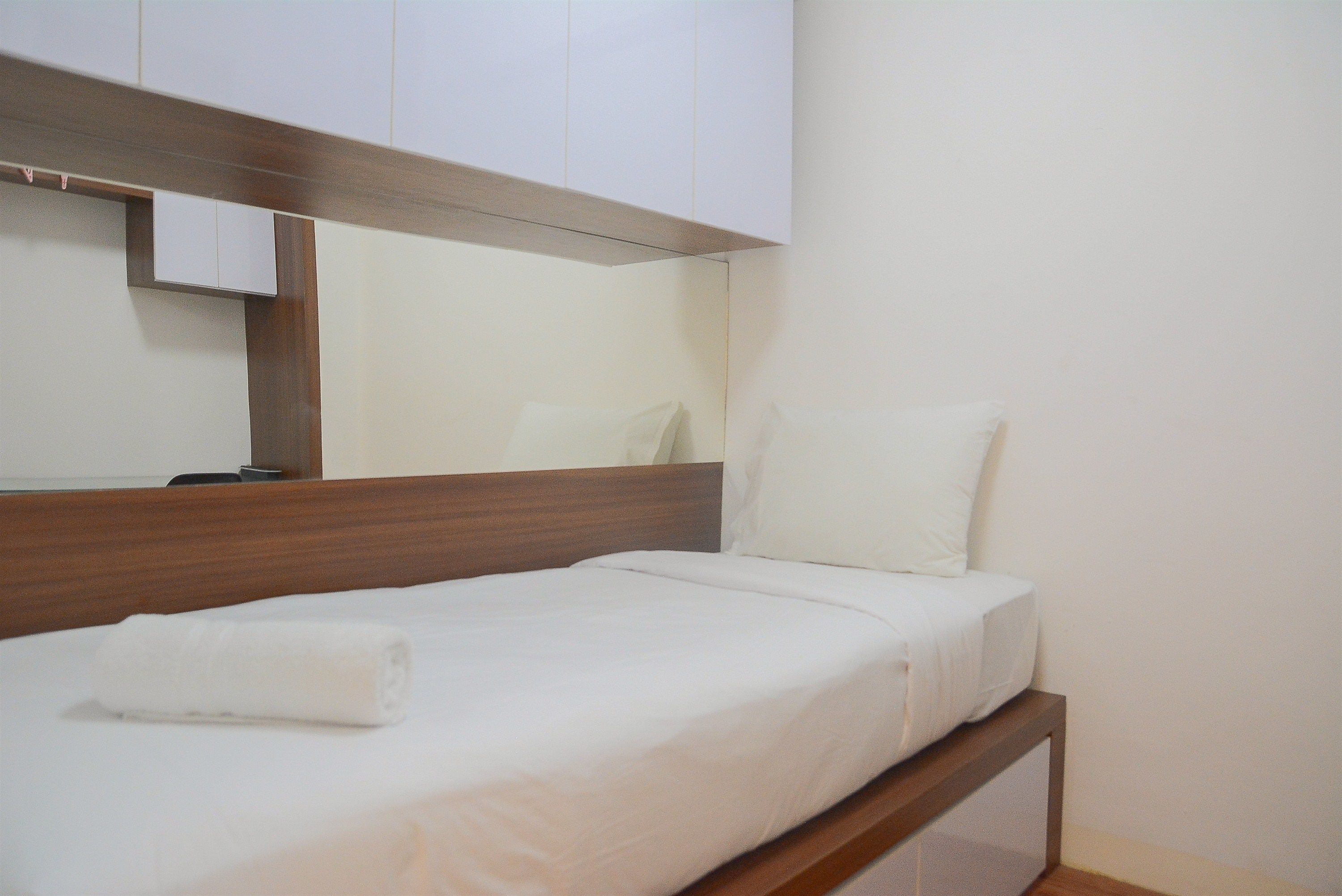 Un lit bien fait, avec une tête de lit en bois et un matelas blanc.