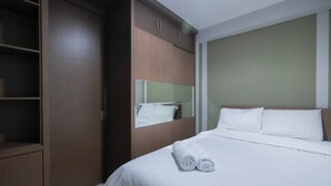 A hotel room with a bed, a wardrobe, and a mirror.