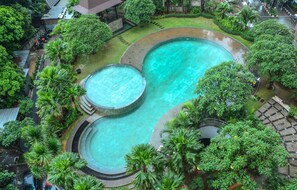 A large outdoor swimming pool surrounded by lush greenery and a covered area. - 2BR with Sofa Bed Cervino Tebet Apartment (Jakarta)