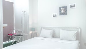 A neatly made bed with white linens, a white chair with a pink cushion, and a ladder leaning against the wall. - New Furnished Studio Apartment @ Woodland Park Residence (Jakarta)