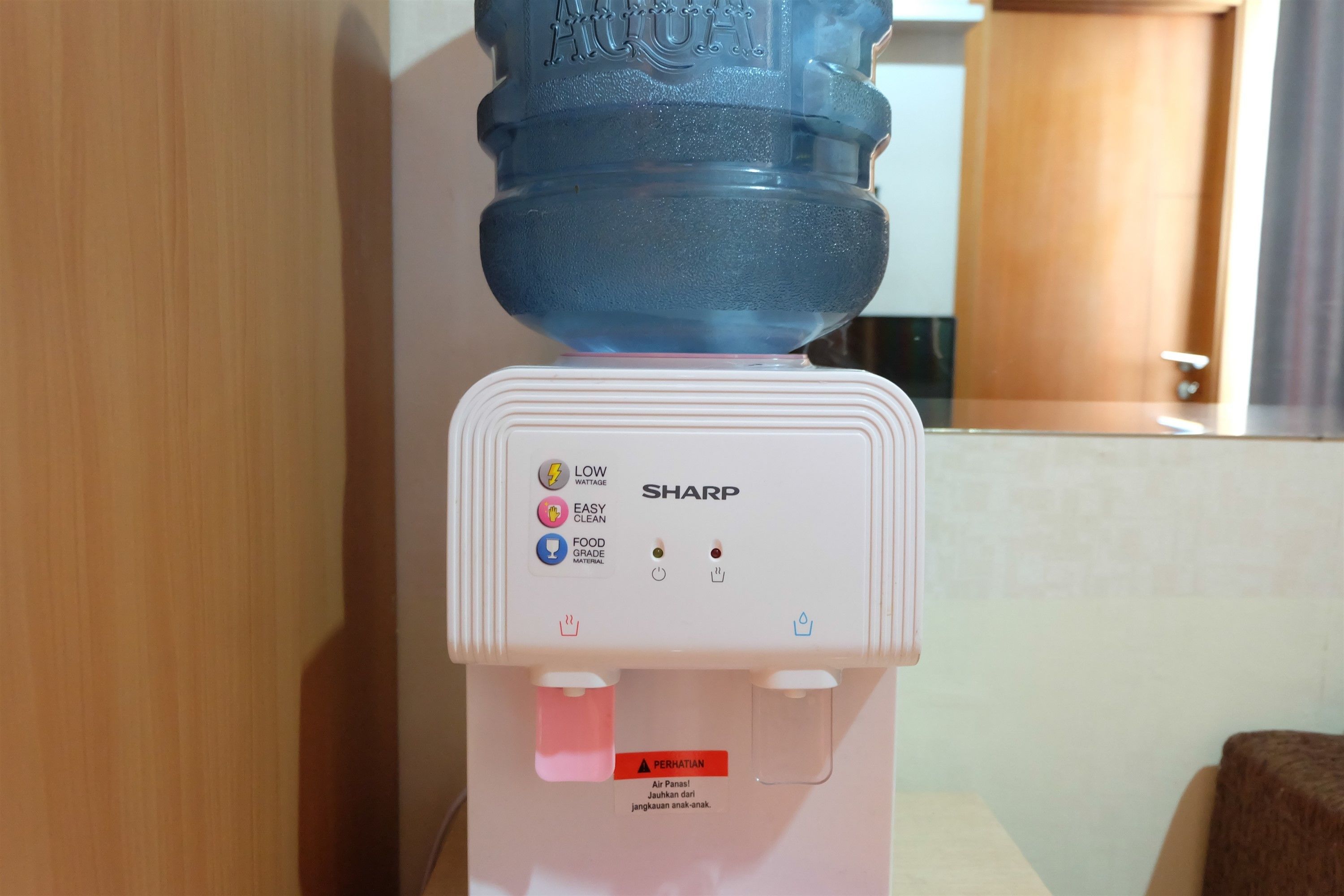 A water dispenser with a large water bottle on top, a control panel with various settings, and a warning label.