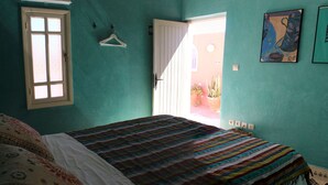 Een slaapkamer met een bed, een raam en een deur die leidt naar buiten.