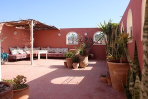 A courtyard with a seating area, potted plants, and a pergola. - Tifawin Apartment (Mirleft)