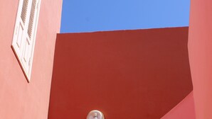Een hoek van een gebouw met een rode gevel en een helderblauwe lucht.