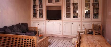 Una sala de estar con un sofá, una mesa de comedor de madera y un televisor sobre un mueble.
