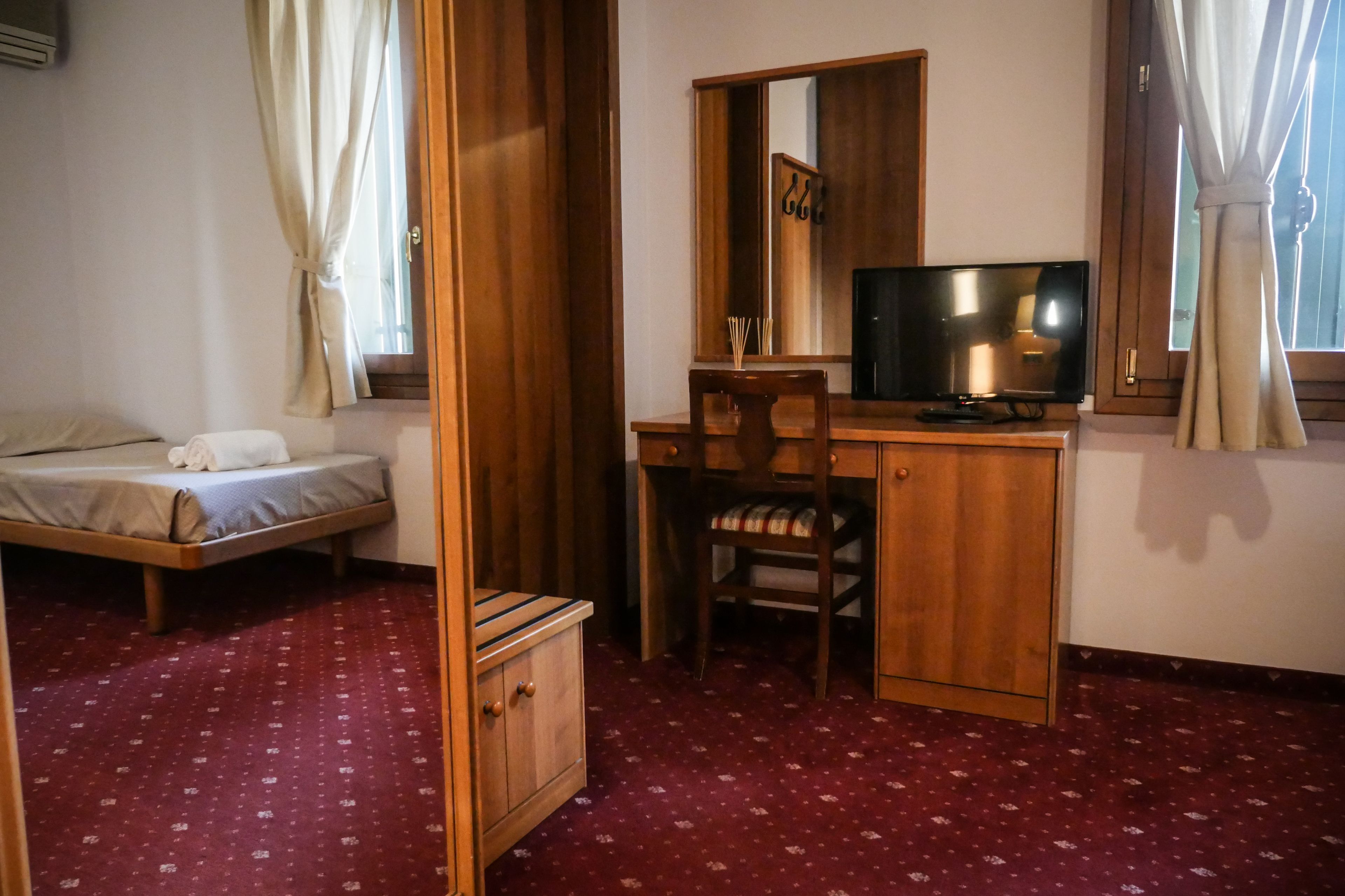Una camera da letto con un letto, una scrivania con una sedia, una televisione e un armadio.