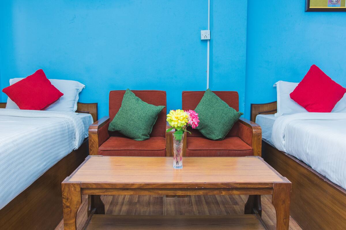 Quarto com duas camas, uma mesa de centro de madeira e um vaso com flores.