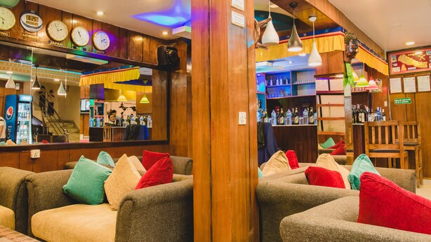 A bar area with wooden paneling, multiple clocks, and a variety of seating options. - Hotel Four Eyes (Kathmandu)