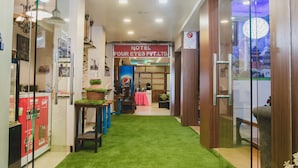 A hotel lobby with a green carpet, a Pepsi advertisement, and a 'PUSH' sign. - Hotel Four Eyes (Kathmandu)