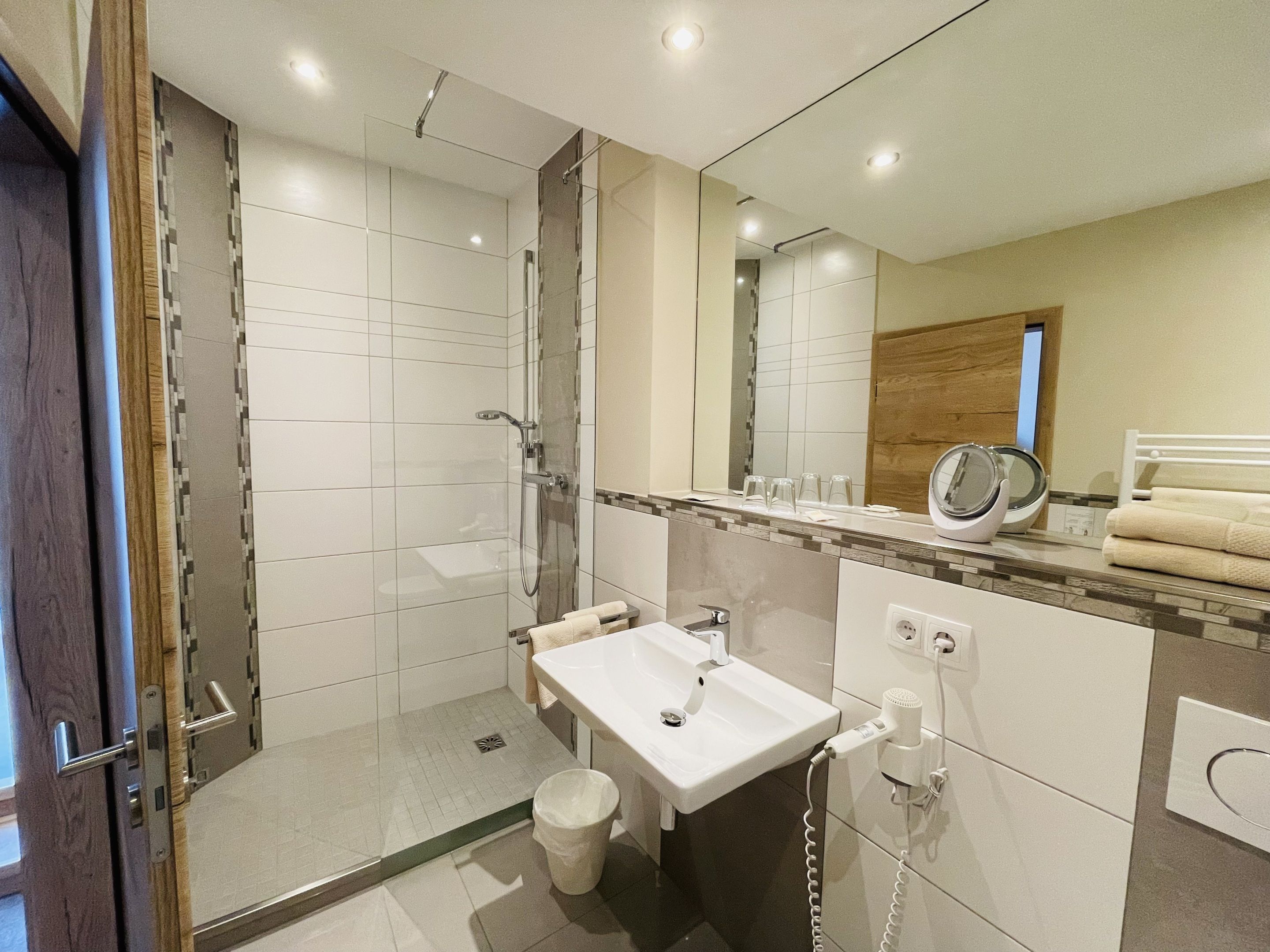 A modern bathroom with a glass-enclosed shower, a white sink, and a vanity with a mirror.