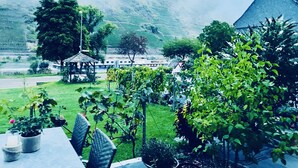 Un jardín con un pabellón, una mesa con sillas y una vista a una montaña y un edificio al fondo.