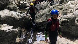 Um grupo de pessoas caminhando por um terreno rochoso com um riacho.