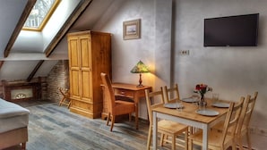 A cozy attic bedroom with a sloped ceiling, wooden furniture, a desk, and a TV. - Windmill Studios (Bucharest)