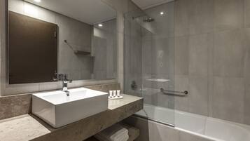 Un baño moderno con un espejo grande, un lavabo y una ducha con cerramiento de vidrio.