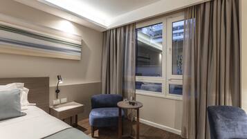 Una habitación de hotel moderna con cama, escritorio, silla, una mesita y ventana con cortinas.