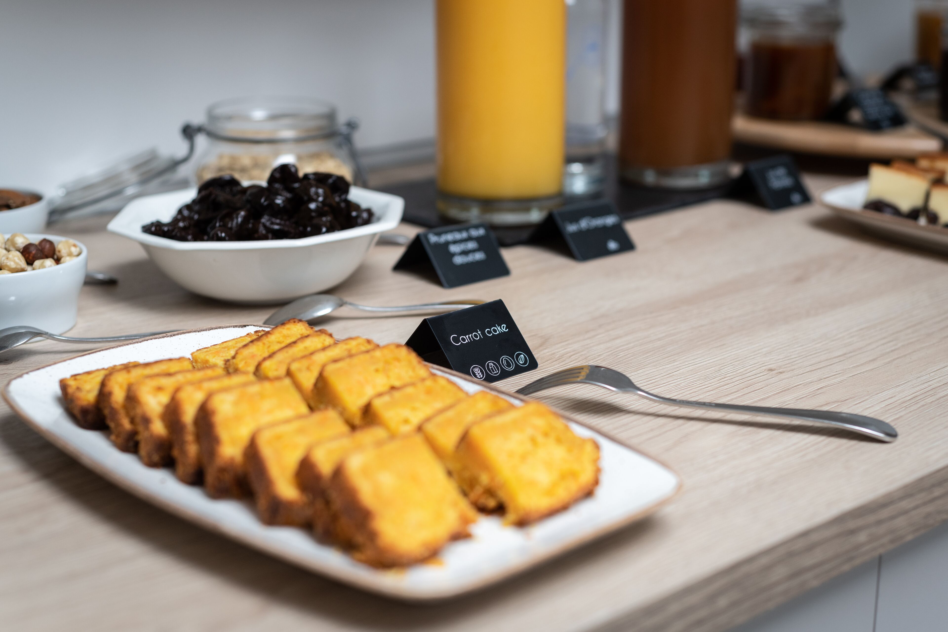 A breakfast buffet with various food items and a sign indicating 'Carrot Cake'.