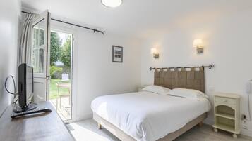 A bedroom with a bed, bedside tables, a desk with a computer, and a window with curtains.