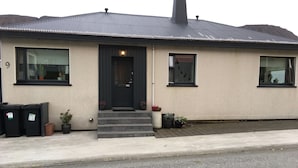 A building with a dark roof, a black door, and a window with a sign that reads "Solheimar". - Sólheimar Studio Apartments (Isafjordur)