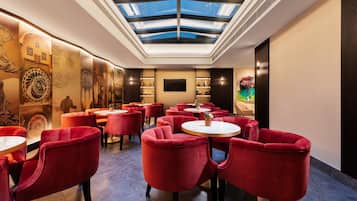 A modern interior with a skylight, red velvet chairs, and a central table.