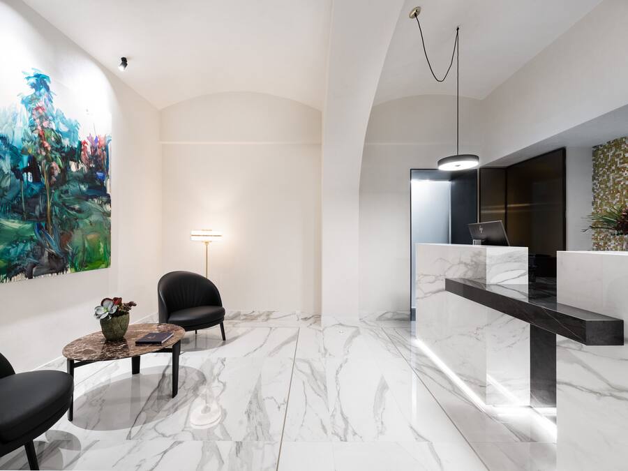 A modern reception area with a marble floor, a reception desk, a large abstract painting, and a black leather chair.