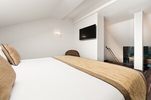 Een moderne slaapkamer met een groot bed, een flatscreen televisie aan de muur en een trap naar een ander niveau.