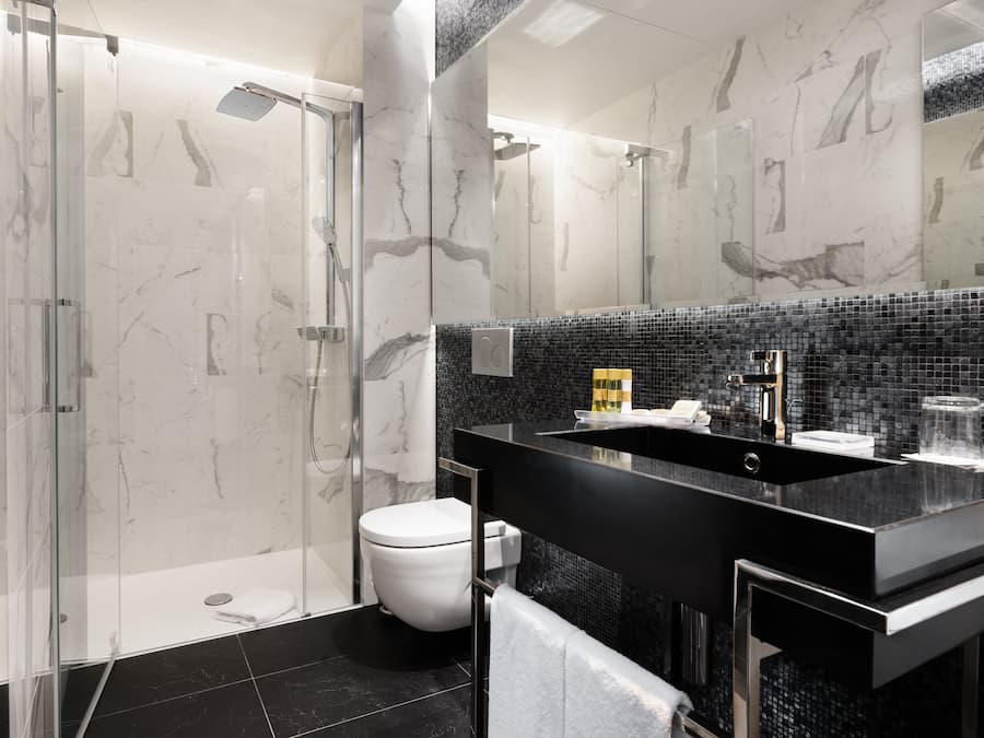 Ein modernes Badezimmer mit einer Duschkabine, einem schwarzen Waschtisch und einer weißen Toilette.