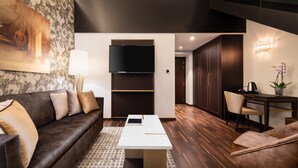 Un salon moderne avec un canapé marron foncé, une table basse blanche et un grand téléviseur à écran plat fixé au mur.