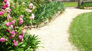 A stone building with a gravel path leading to a seating area. - Le Clos Ayanna (Crémieu)