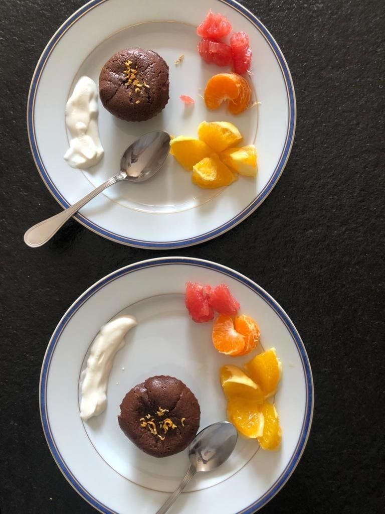 Twee borden met desserts en fruit op een donker oppervlak.