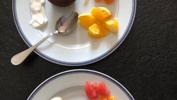 Twee borden met desserts en fruit op een donker oppervlak.
