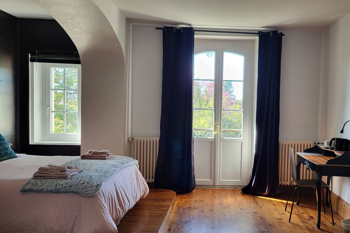 Ein Schlafzimmer mit einem Bett, einem Schreibtisch und einem Fenster mit Vorhängen.