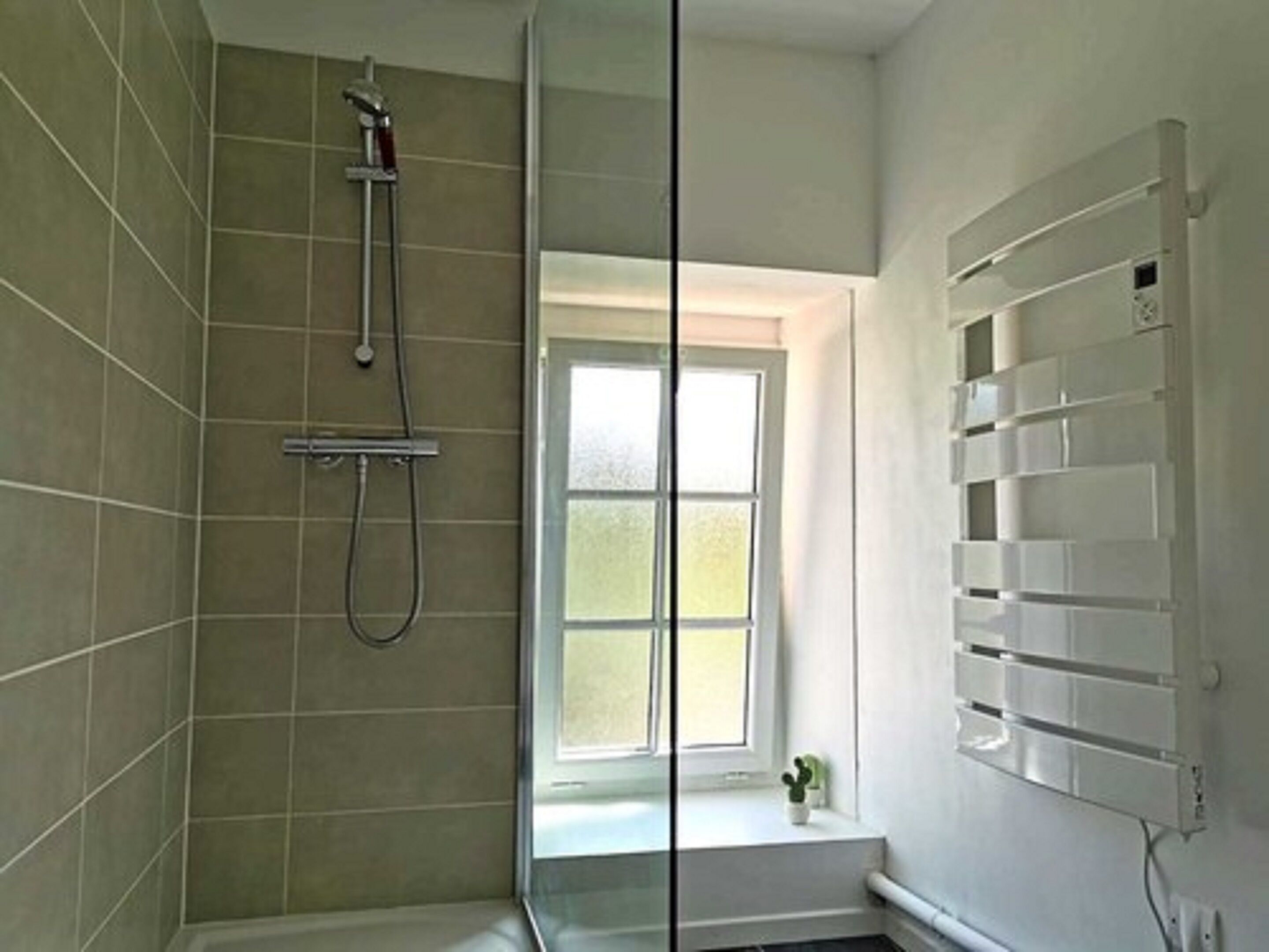 Un baño con ducha, ventana y estante empotrado.