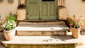 A building entrance with a green door, steps, and potted plants. - La Calade (Montouliers)