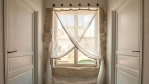 A room with a large window, white walls, and a wooden floor. - La Calade (Montouliers)