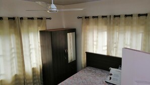 A bedroom with a bed, a wardrobe, a ceiling fan, and curtains. - Salomey Plaza (Kwabenya)