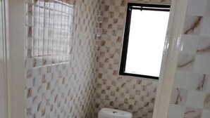 A small bathroom with a toilet, a window, and patterned walls. - Salomey Plaza (Kwabenya)