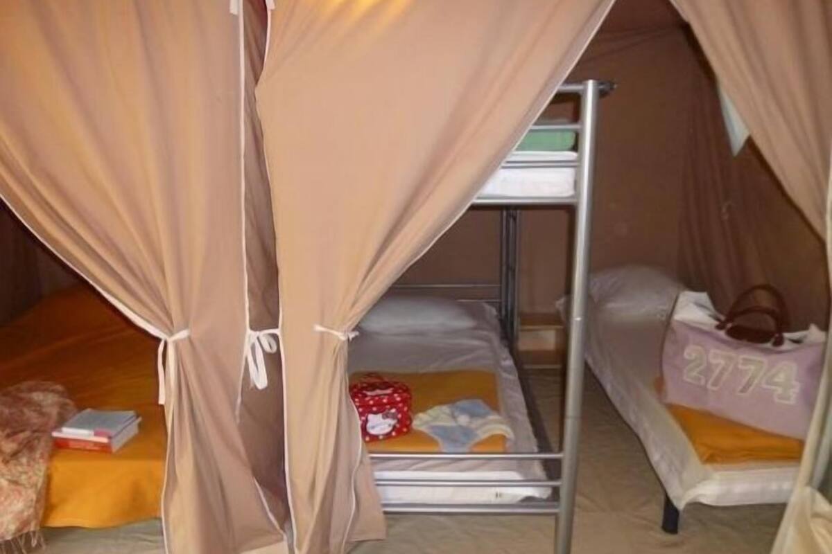 A bunk bed room with a canopy, a suitcase, and a pillow with the number 2774.
