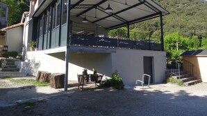 Un edificio de dos plantas con un patio cubierto, una escalera que conduce al piso superior y vistas de un paisaje montañoso.