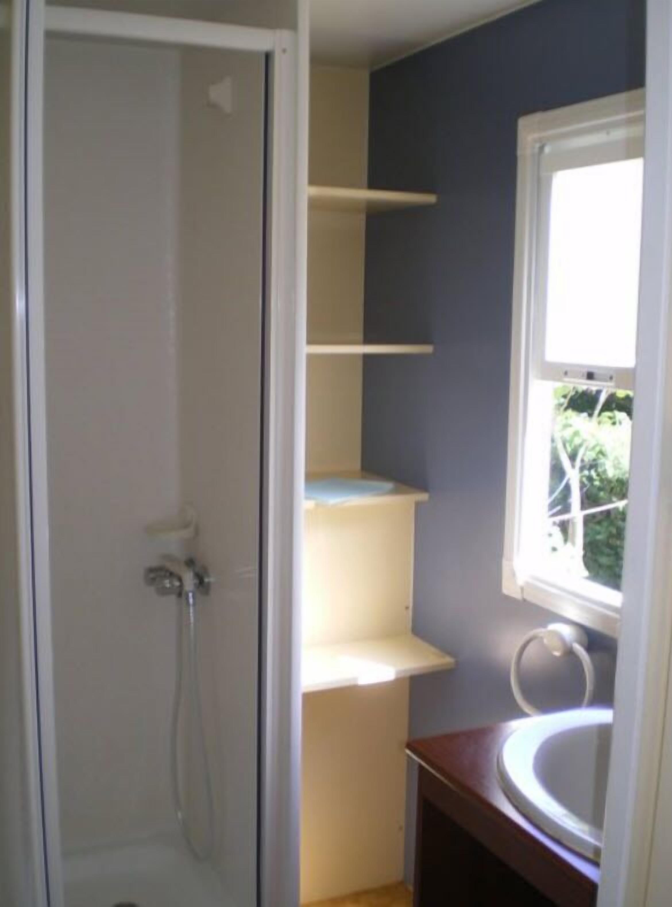 Un baño con ducha, inodoro y ventana.