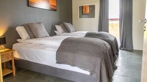A hotel room with a large bed, a bedside table, and a view of the outside through a window. - Hrafntinna Villa (Selfoss)