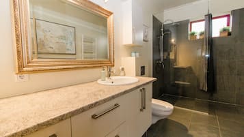 Ein modernes Badezimmer mit einem großen Spiegel, einem Waschbecken und einer Dusche.