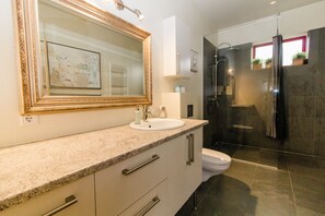 A modern bathroom with a large mirror, a sink, and a shower.