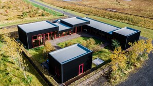 A modern building with a flat roof, a central courtyard, and a surrounding landscape. - Hrafntinna Villa (Selfoss)